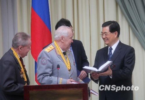 俄羅斯老戰士佩戴著獎章，把一本書作為禮物送給胡錦濤。中新社發張朔攝